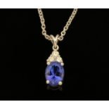 An 18 ct white gold pendant on chain, set with an oval cut tanzanite and diamonds,