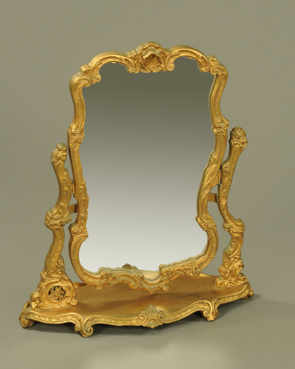 A gilt painted wooden dressing table mirror, shell and scroll carved with shaped base.