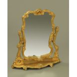A gilt painted wooden dressing table mirror, shell and scroll carved with shaped base.