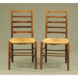 A pair of 19th century oak ladder back chairs with rush seats raised on turned legs.