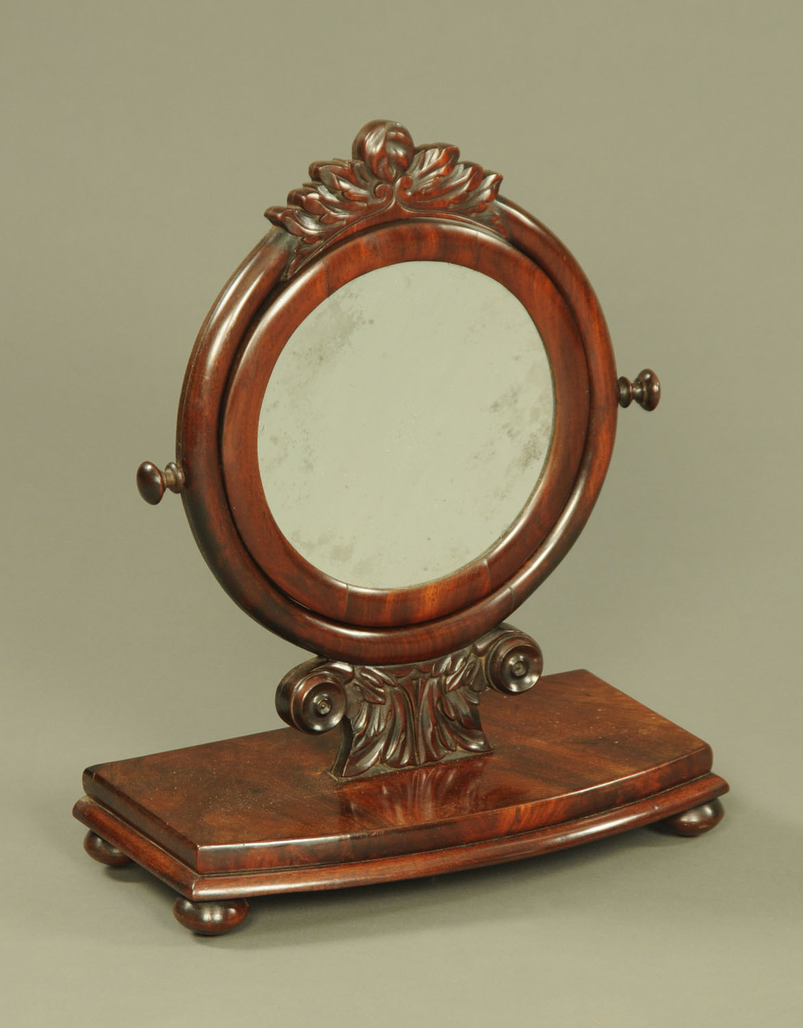 A Victorian mahogany circular mirror, with carved frame and bowfronted stand.