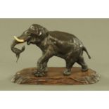 A 19th century Japanese bronze elephant, Meiji period with ivory tusks and raised on a wooden stand.