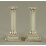 A pair of silver table candlesticks, with fixed sconces and beaded square bases,