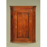 A George III oak and mahogany crossbanded hanging corner cupboard,