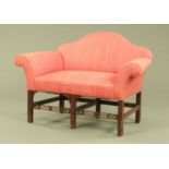 A George III style mahogany small settee, with arched back, rollover arms,
