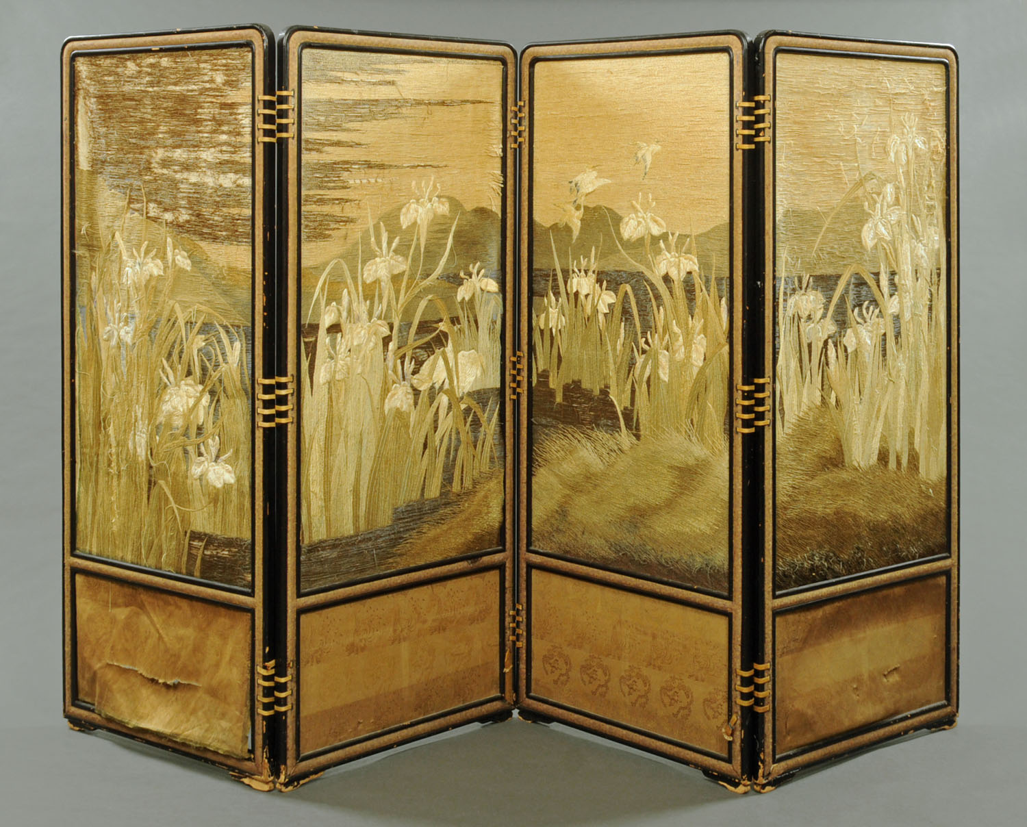 A 19th century Japanese Meiji period fourfold lacquered screen with handworked textile panels.