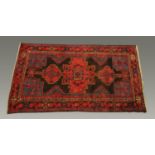 An Eastern fringed rug, with centre rectangular panel and repeating line border,
