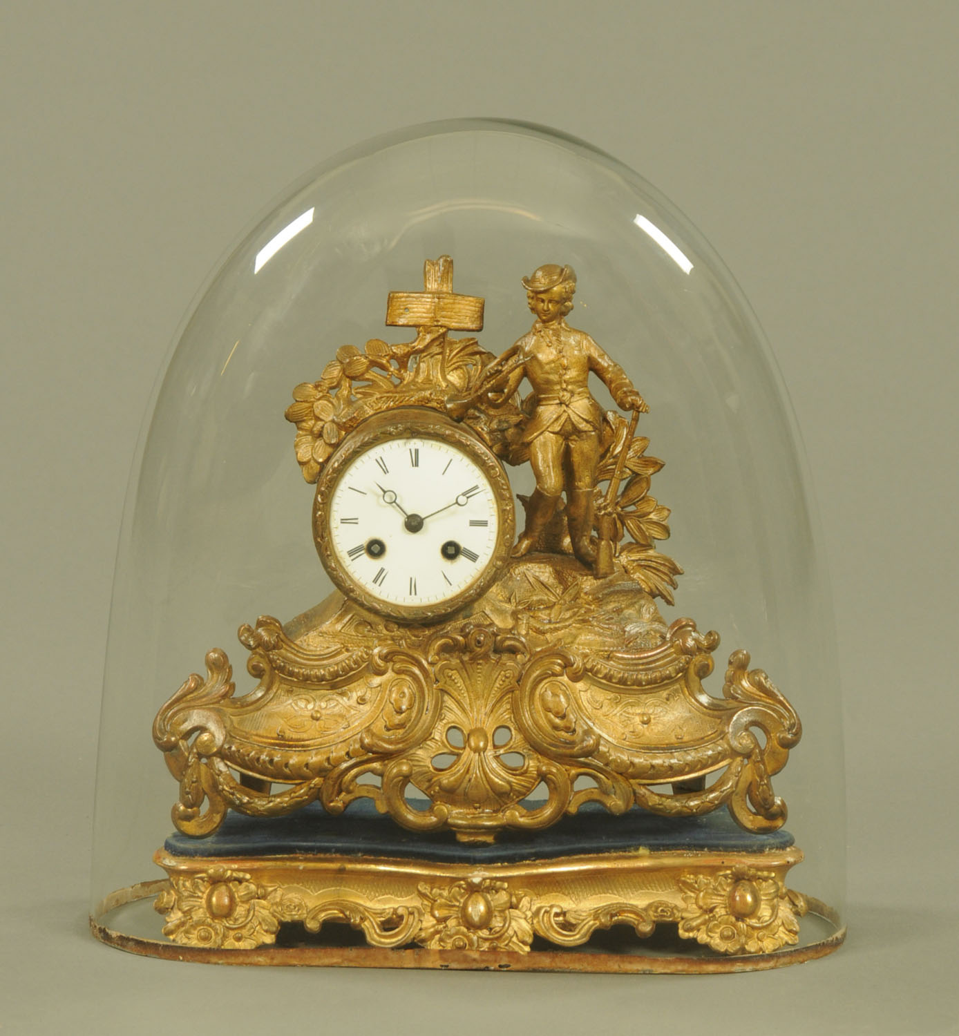 A 19th century French spelter figural mantle clock, with giltwood base and glass dome.
