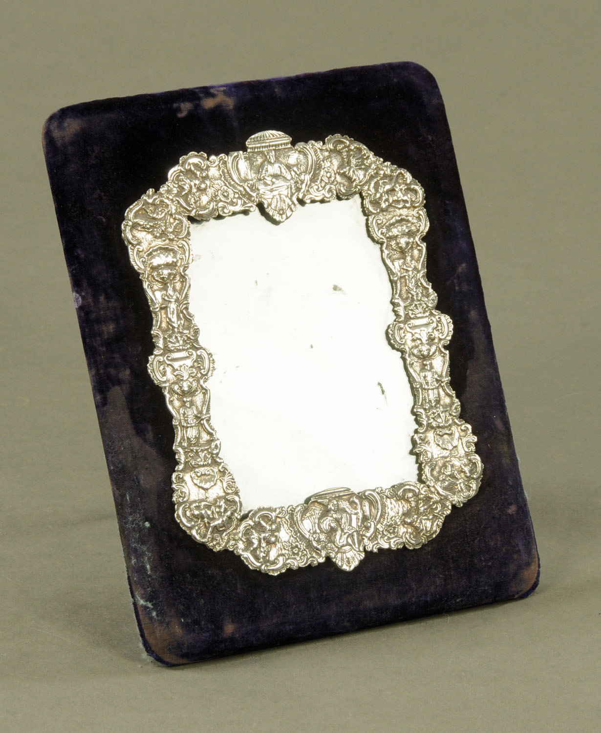 A white coloured metal photograph frame, decorated with figures and scrollwork,