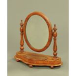 A Victorian mahogany oval framed toilet mirror, the base with lidded compartment. Width 56 cm.