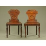 A pair of 19th century oak hall chairs, with carved and shaped backs,