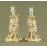 A pair of continental porcelain figural candlesticks, each of a lady with child, floral encrusted.