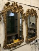 A pair of gilt framed mirrors with cherub and scroll decoration
