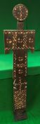 A tribal carved and painted wooden standing figure with all over geometric style decoration in red,