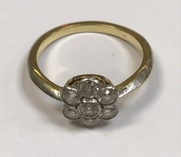 An unmarked yellow and white metal diamond cluster ring the seven stones of flower head form approx.