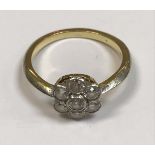 An unmarked yellow and white metal diamond cluster ring the seven stones of flower head form approx.