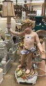 An early 20th Century Schierholz porcelain table lamp as a cherub holding aloft a torch