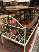 A white painted scroll decorated wrought iron day bed