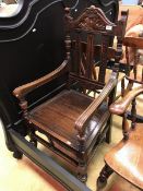 A Victorian carved oak-framed open arm hall chair with panelled seat