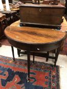 An Edwardian mahogany demi-lune fold over card table on square tapering legs on brass castors