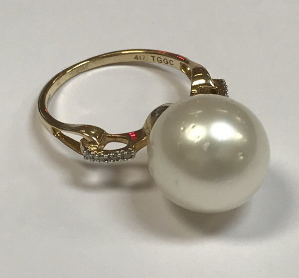 A 10 carat gold mounted South Sea pearl ring, the shoulders set with four small diamonds,