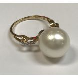 A 10 carat gold mounted South Sea pearl ring, the shoulders set with four small diamonds,