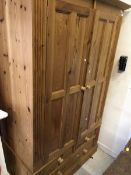 A modern pine two door wardrobe over two short and one long drawer and a modern pine knee hole