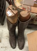 A pair of brown leather riding boots, together with a brown leather whip,