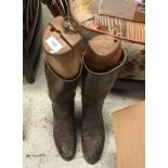 A pair of brown leather riding boots, together with a brown leather whip,