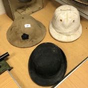 A collection of various hats including tropical pith helmet, Herbert Johnson bowler,