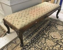 A Victorian rosewood framed long stool with floral needlework top raised on cabriole legs to scroll