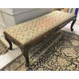 A Victorian rosewood framed long stool with floral needlework top raised on cabriole legs to scroll