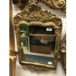 A circa 1700 carved giltwood and gesso framed wall mirror in the Rococo style
