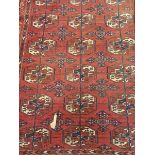 A Bokhara rug, the central panel set with repeating elephant foot medallions on a red ground,