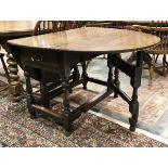 A 19th Century oak oval gateleg drop-leaf dining table on baluster-turned supports