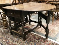 A 19th Century oak oval gateleg drop-leaf dining table on baluster-turned supports