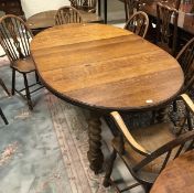 An early 20th Century oak oval draw-leaf dining table on barley-twist supports,