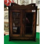 A circa 1900 oak smoker's cabinet with two glazed doors enclosing two drawers and three-section