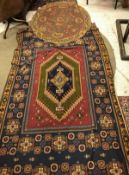 Two Caucasian carpets, one with rectangular central panel on a red ground, within a stepped blue,