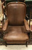 A Victorian reclining open arm elbow chair with brown leather upholstery and mahogany frame with
