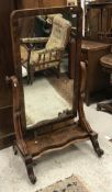 A Victorian figured mahogany-framed cheval mirror on S-scroll supports to the platform form base on