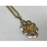 A nine carat gold and topaz set pendant of stylised flower form on a nine carat gold chain