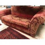 A modern upholstered scroll-arm shaped back sofa with gold floral on red upholstery