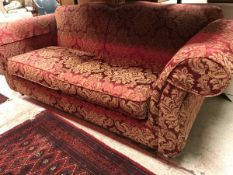 A modern upholstered scroll-arm shaped back sofa with gold floral on red upholstery