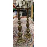 A pair of brass ecclesiastical style pricket candlesticks on turned and triangular form columns