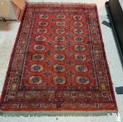 A Bokhara rug with all over elephant foot medallions on a red ground within a square medallion
