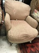 A Victorian armchair raised on ringed and turned front legs to brass caps and china casters