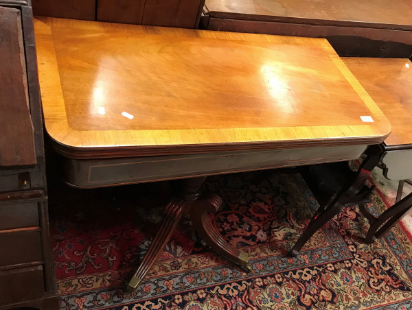 An early 19th Century mahogany tea table the cross-banded foldover top over a satinwood strung