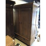 A Continental waxed pine two door wardrobe with drawer on bun feet