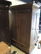 A Continental waxed pine two door wardrobe with drawer on bun feet